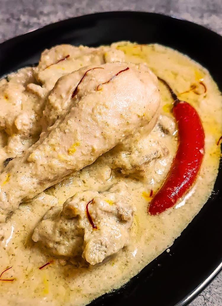 Chicken rezala in pale white gravy with a single red chilli and saffron strands